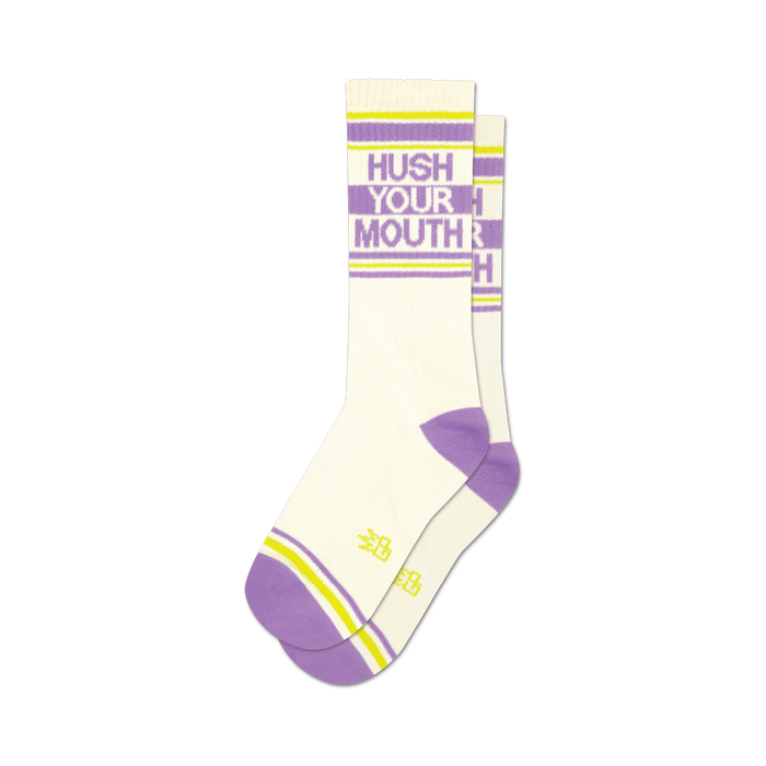 Pair of white crew socks with purple and yellow stripes. Text 'Hush Your Mouth' is displayed on the socks in purple. }}