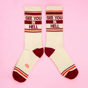 Another flat lay of 'See You In Hell' socks, slightly different angle on pink background.