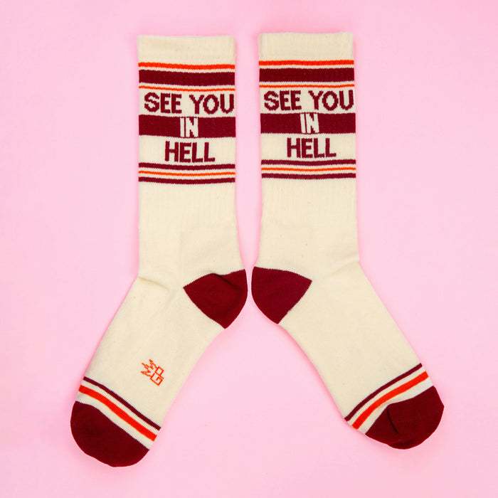 Another flat lay of 'See You In Hell' socks, slightly different angle on pink background.