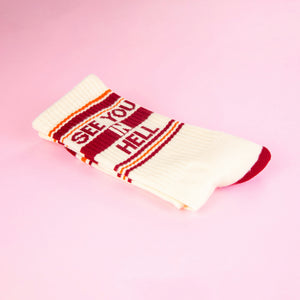 Close-up of a single 'See You In Hell' sock folded on a pink background.