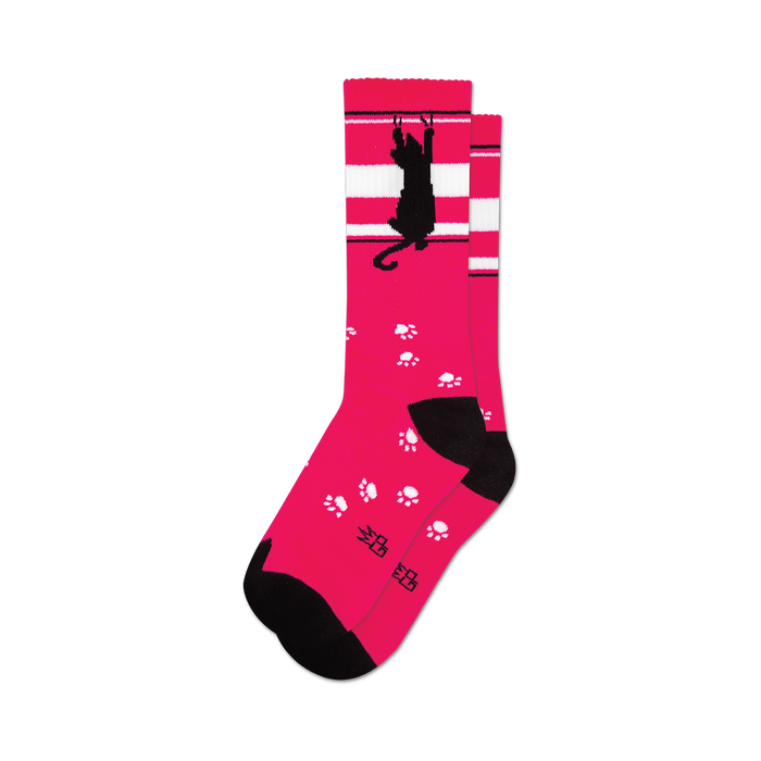 Pair of pink crew socks featuring a black cat scratching design and white paw prints. White stripes accent the top. }}