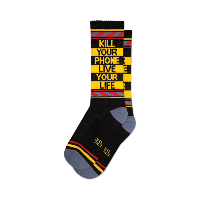 A pair of black crew socks with yellow and red stripes. The socks feature the text 'KILL YOUR PHONE LIVE YOUR LIFE' in yellow. }}