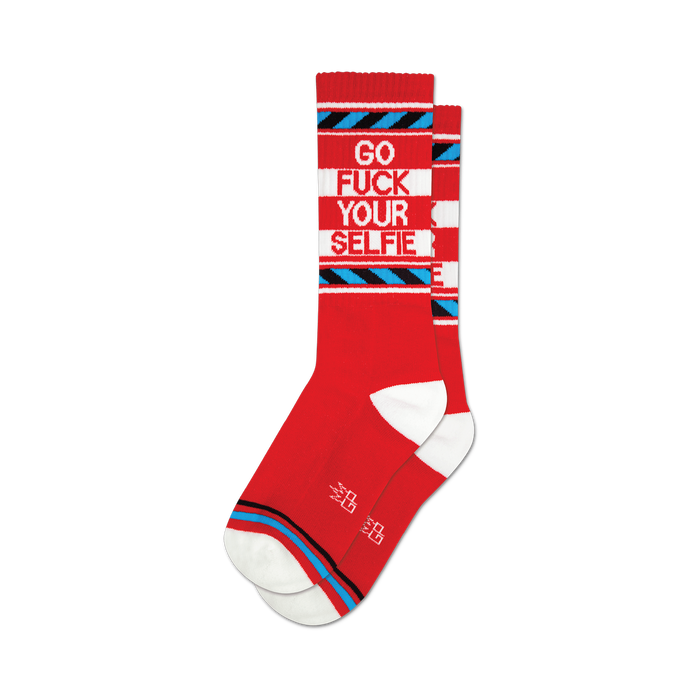 Pair of red crew socks with a bold 'Go Fuck Your Selfie' message in white and blue. Features blue and white stripes.