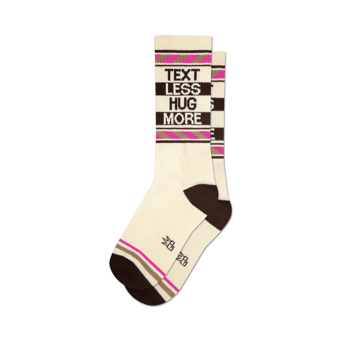 Pair of cream crew socks with brown and pink stripes. The words 'Text Less Hug More' are displayed vertically on the socks. }}