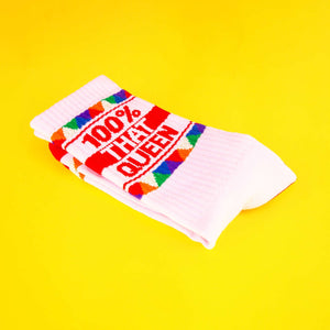 Close-up of the folded '100% That Queen' socks on a yellow background.
