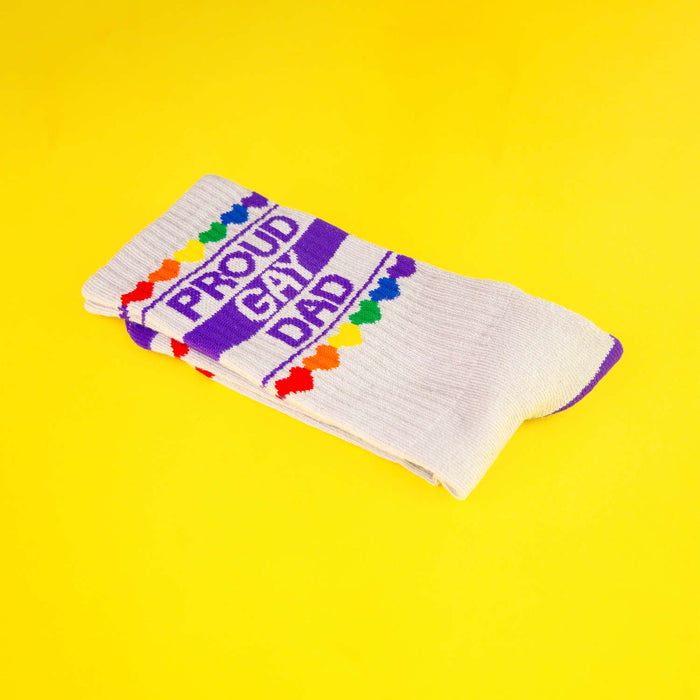 Folded 'Proud Gay Dad' sock on a yellow background.