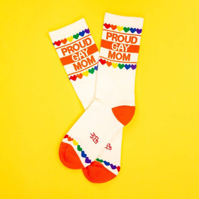Pair of 'Proud Gay Mom' socks on a yellow background, laid out in an 'X' shape.