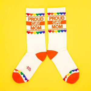 Another flatlay shot of the 'Proud Gay Mom' socks on a yellow background. Socks laid parallel.