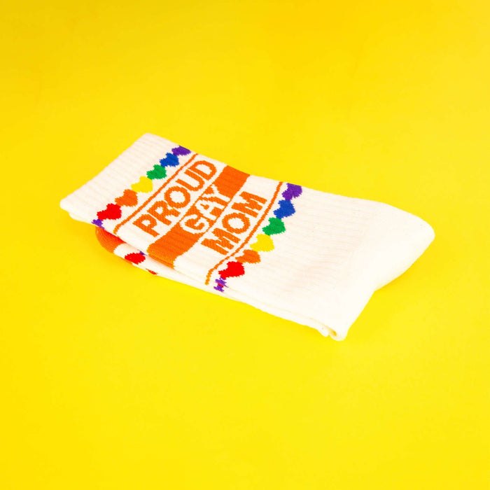 Close-up of folded 'Proud Gay Mom' socks on a yellow background.