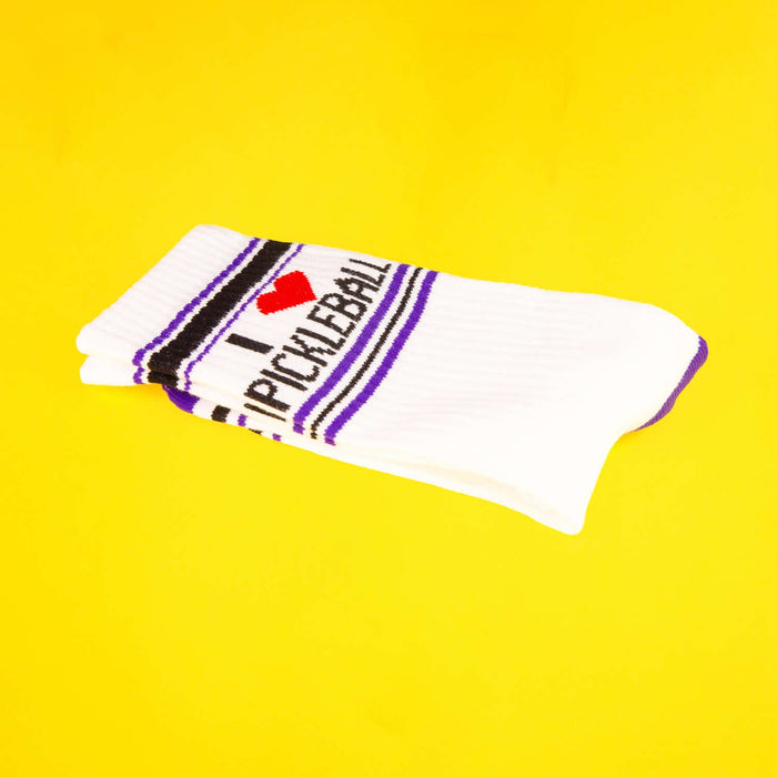 Close-up of folded 'I Heart Pickleball' sock on yellow background.