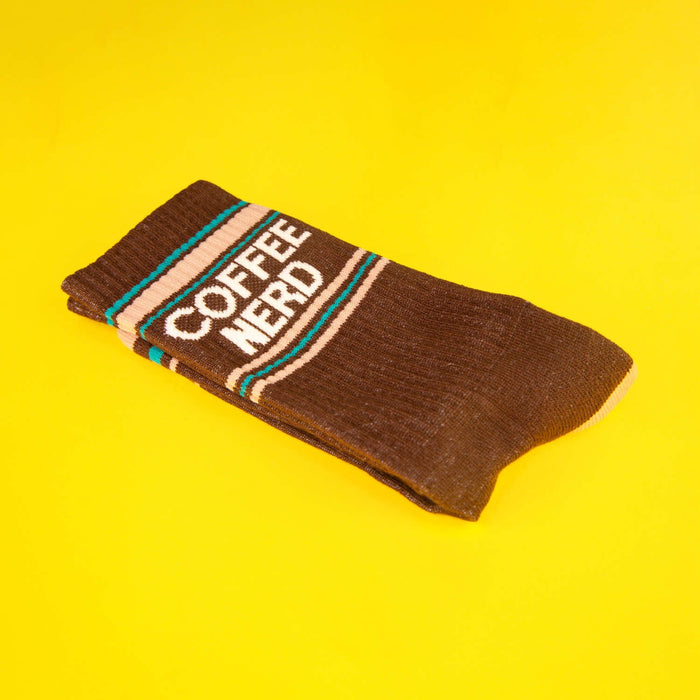 Close-up of a folded brown Coffee Nerd sock on a yellow background. Shows texture and detail of the design.