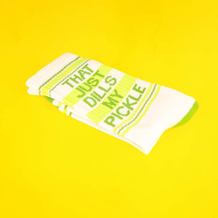 Close-up of folded 'That Just Dills My Pickle' socks on a yellow background.