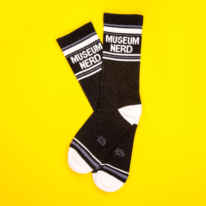 Museum Nerd socks on a yellow background; flat lay.