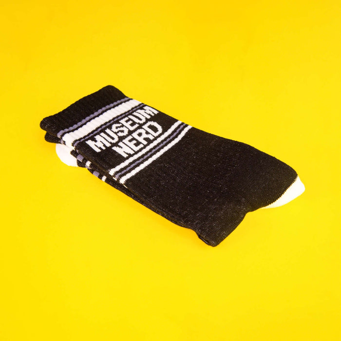 Folded Museum Nerd socks on a yellow background.