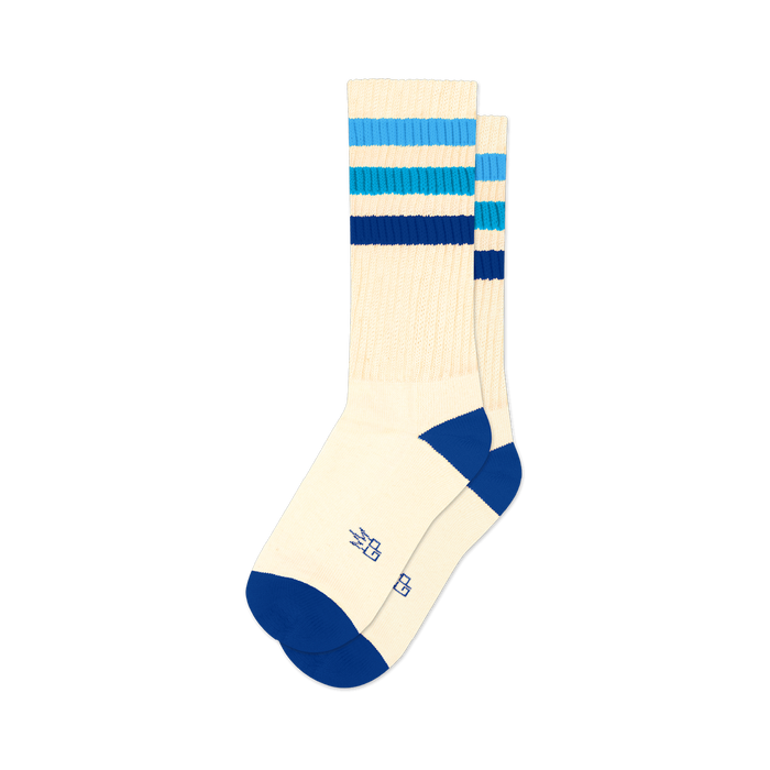 Pair of off-white crew socks with horizontal blue stripes in varying shades. Blue accents at the heel and toe. Retro style.