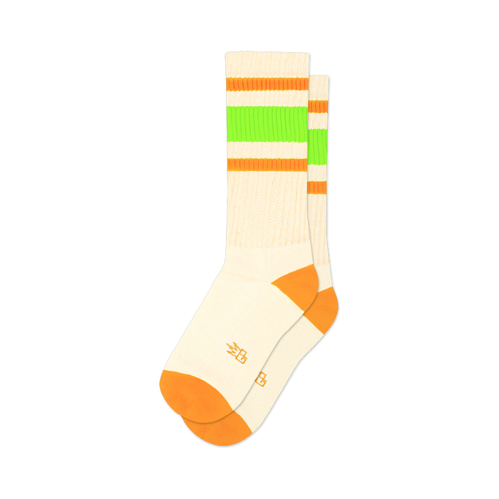Pair of off-white crew socks with orange and neon green stripes. Orange accents at the toe and heel.  Retro style.