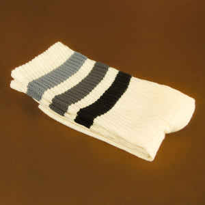 Close-up shot of a single off-white crew sock folded against a brown background.