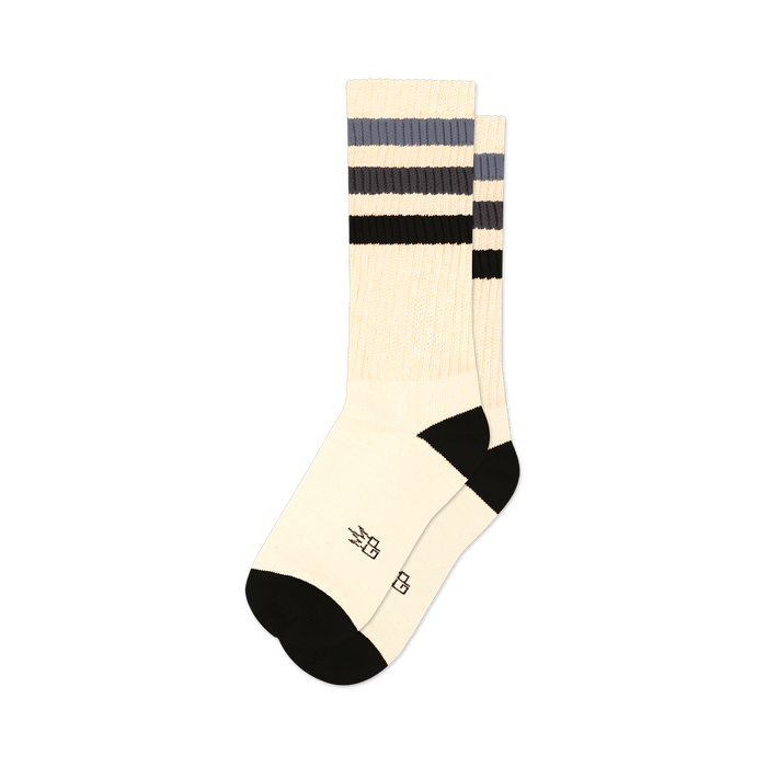 Pair of off-white crew socks with black and grey horizontal stripes. Black cuffs and subtle embroidered logo.