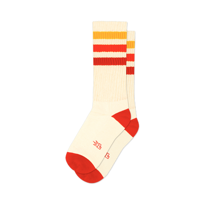Pair of cream crew socks with red, orange, and yellow horizontal stripes. Red accents at the heel and toe. Small logo on the bottom.