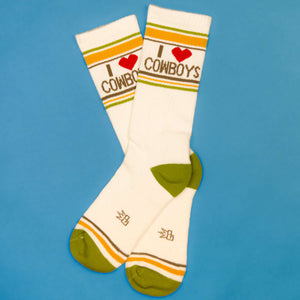 Flat lay of 'I love cowboys' socks on a blue background.