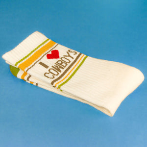 Close-up of folded 'I love cowboys' sock on a blue background, showcasing detail.