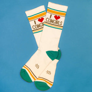 Flat lay of 'I Heart Cowgirls' socks on a blue background.