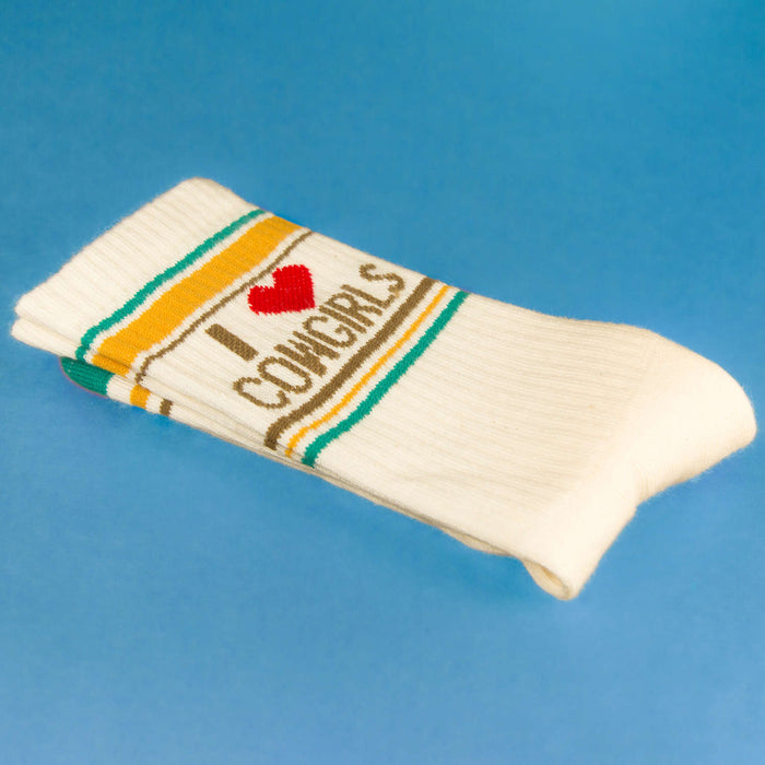 Close-up of folded 'I Heart Cowgirls' socks on a blue surface.