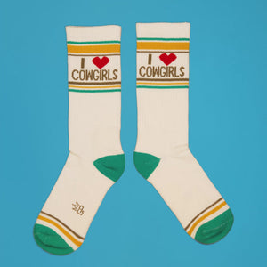 Pair of 'I Heart Cowgirls' socks laid flat on a blue background.