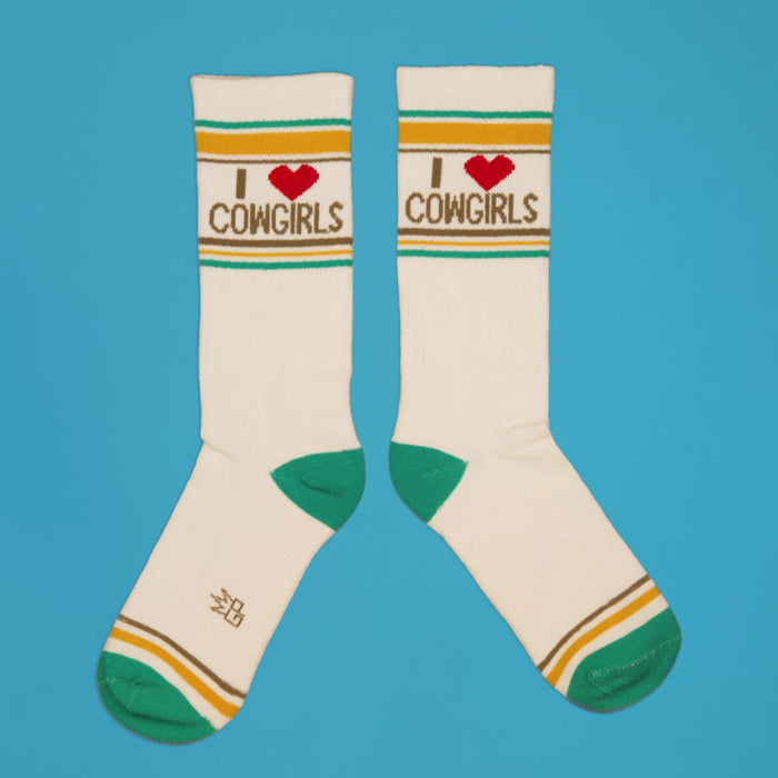 Pair of 'I Heart Cowgirls' socks laid flat on a blue background.