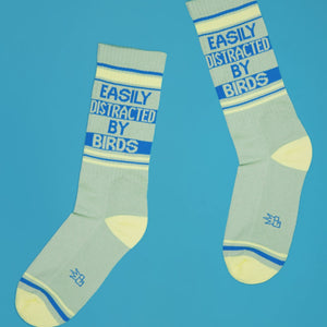 Two 'Easily Distracted By Birds' socks laid out on a blue background, showcasing the full design.