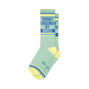 Pair of sage green crew socks with yellow and blue stripes. Text reads,