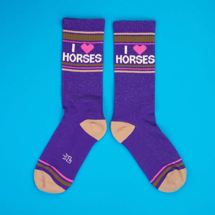Another flatlay showcasing the purple 'I Heart Horses' socks against a blue backdrop.