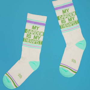 Pair of 'My Garden Is My Therapist' socks arranged casually on a bright blue background.