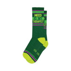 Pair of dark green crew socks with lime green and purple stripes and the text 'Weed Is My Therapist'.
