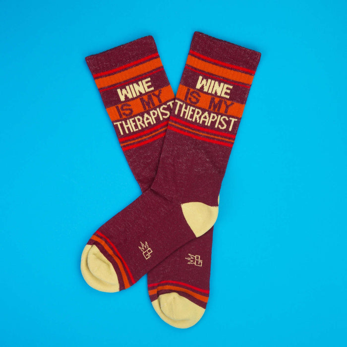 Pair of 'Wine Is My Therapist' socks on a blue background.
