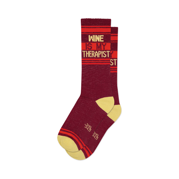 Pair of burgundy crew socks with orange and yellow stripes and the text 'Wine Is My Therapist'.