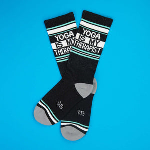Flatlay of 'Yoga Is My Therapist' socks against a bright blue background.