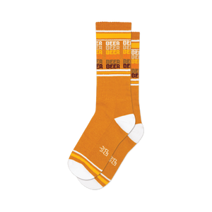Pair of mustard yellow crew socks with horizontal stripes that say 'Beer' in a retro style font.  White and orange accents.