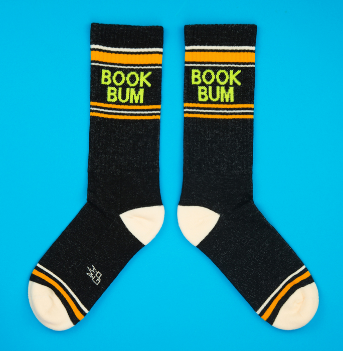 Flatlay product shot of a pair of black 'Book Bum' socks on a bright blue background.