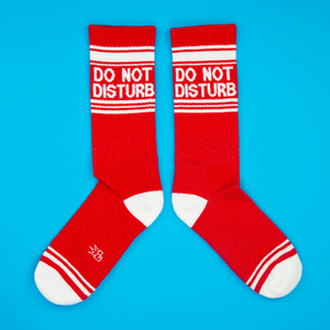 Flat lay of a pair of red 'Do Not Disturb' crew socks on a blue background.