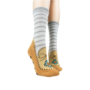 Lifestyle shot showing the moccasin slipper socks on a person's feet. Grey and tan colors are displayed.