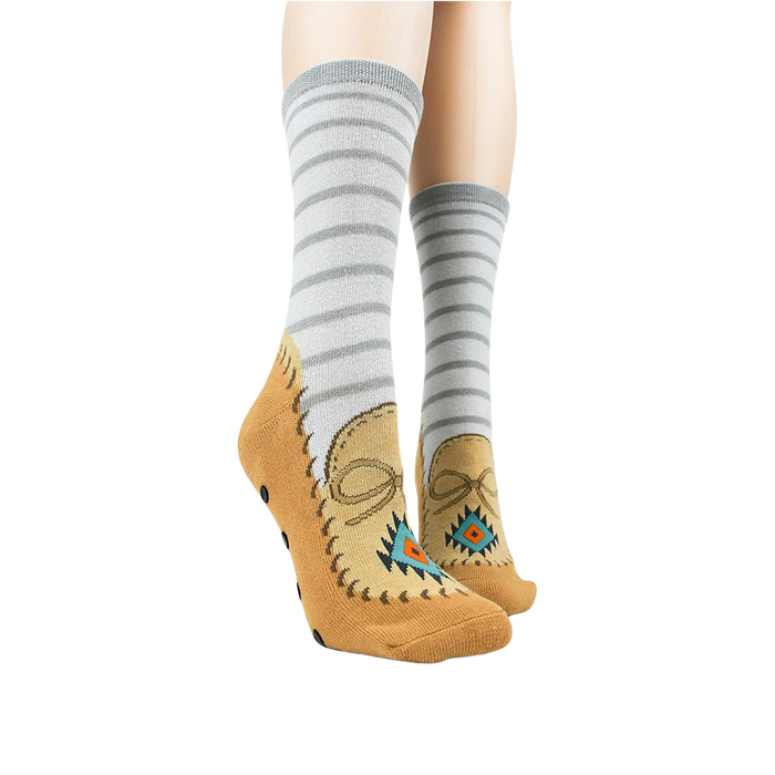 Lifestyle shot showing the moccasin slipper socks on a person's feet. Grey and tan colors are displayed.