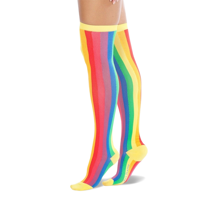 A pair of women's over-the-knee socks with vertical rainbow stripes. The socks are predominantly red, orange, yellow, green, blue, and purple, with yellow cuffs. }}