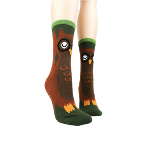 A pair of brown socks with green trim at the top and non-slip treads on the bottom.
