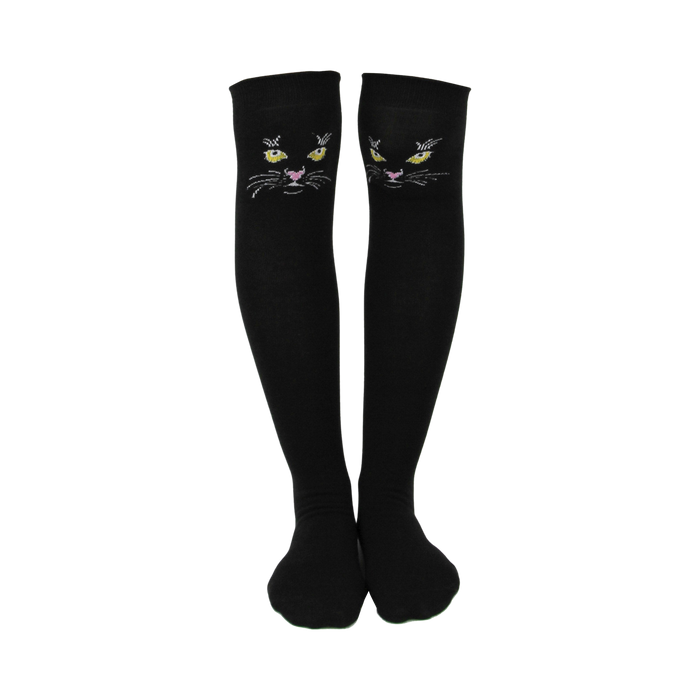Pair of black knee-high socks with embroidered black cat faces featuring yellow eyes and pink noses. }}
