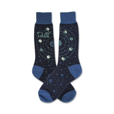 Pair of navy blue crew socks with a celestial design.  Features a repeating pattern of planets orbiting a star, and the text 'It's Just A Phase'.