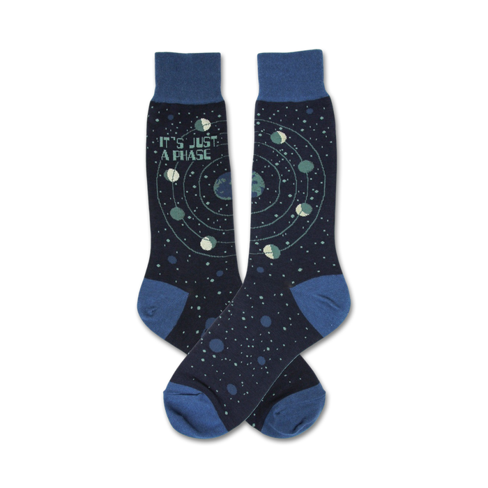 Pair of navy blue crew socks with a celestial design. Features a repeating pattern of planets orbiting a star, and the text 'It's Just A Phase'. }}