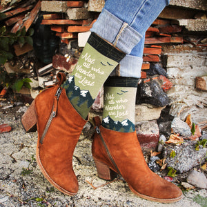 A person wearing mid-calf brown leather boots with a stacked heel and green socks with the text 