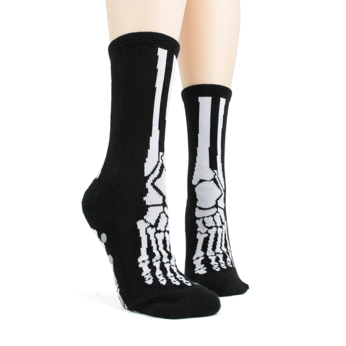 Lifestyle shot of model wearing black skeleton socks with grey non-skid bottoms.