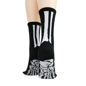 Rear view of model's legs wearing black skeleton socks with grey non-skid bottoms against a black background.